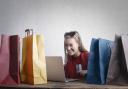 A woman shopping online surrounded by shopping bags. Credit: Canva