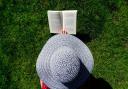 A woman in a hat reading. Credit: Canva