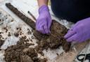 Experts from Wessex Archaeology carefully clean the spade of excess mud as part of the conservation process