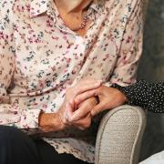 Photo by PA of a care home resident holding hands with her daughter.