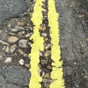 Council workers have come under fire after painting double yellow lines through the centre of potholes