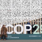 An attendee sits on a sign for the Cop29 UN Climate Summit (Sergei Grits/AP)