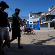 Foreign tourists walk past the closed Nana Backpackers hostel in Vang Vieng (Anupam Nath/AP)