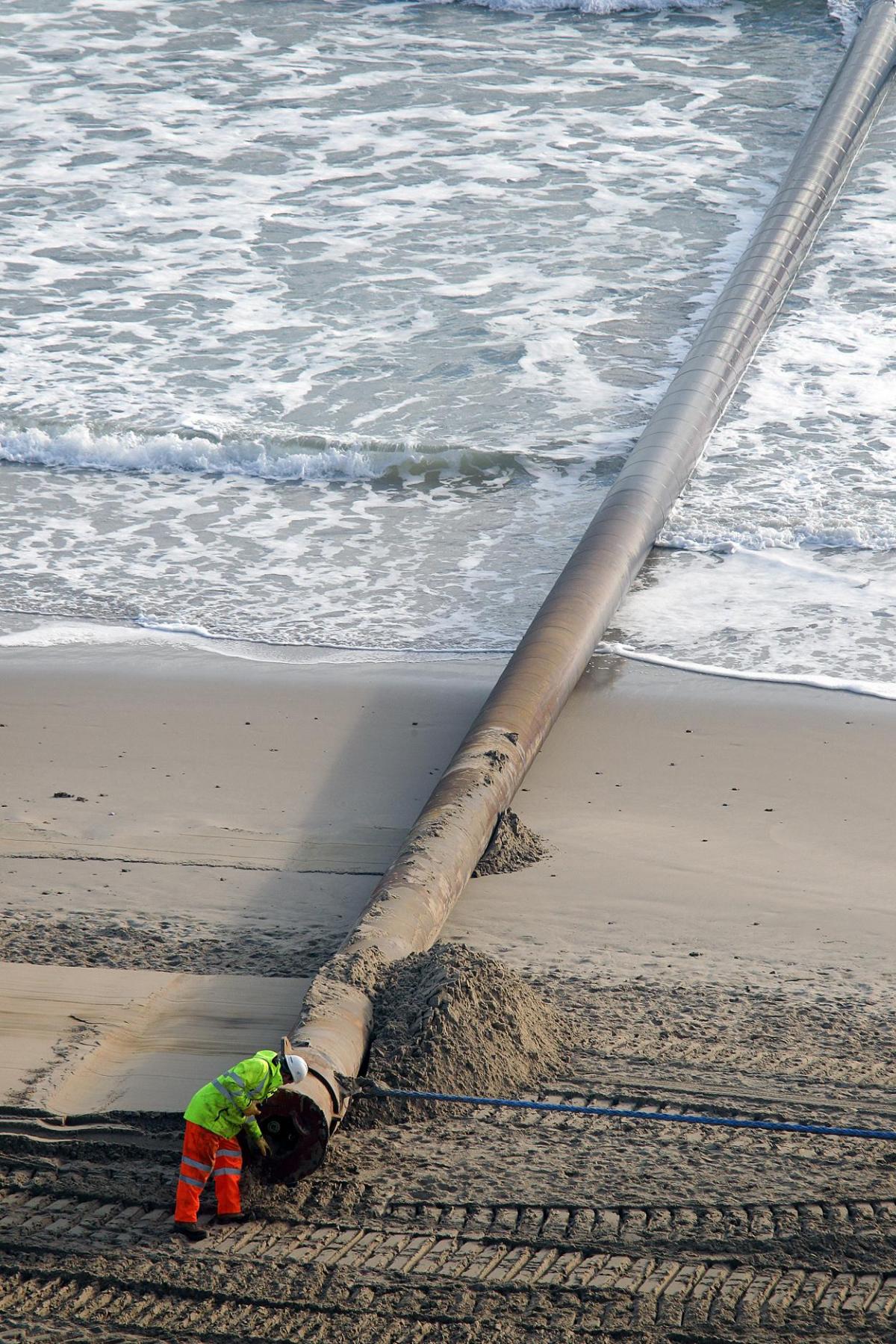 The 700m pipe used to protect Poole's beaches from coastal erosion after the winter storms is removed from Canford Cliffs. Photos by Sally Adams. 